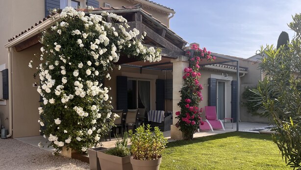 Ein Haus mit überdachter Terrasse, Sitzgelegenheit im Freien und einem gepflegten Garten.