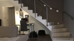 Ein modernes Interieur mit Treppe, Sofa, Schreibtisch und Stuhl.