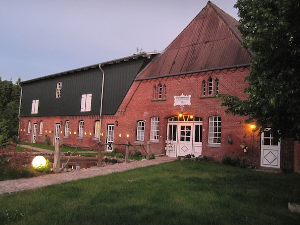 Ein rotbacksteiner Gebäude mit schwarzem Dach, einem Schild mit der Aufschrift "Pattikier Haus" und einem kleinen Garten mit einem Weg zum Eingang.