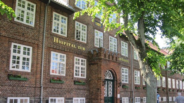 Un edificio storico con facciata in mattoni, numerose finestre e una porta d'ingresso verde.
