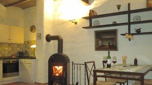 Una cucina accogliente con stufa a legna, un tavolo da pranzo con sedie e una macchina da caffè.