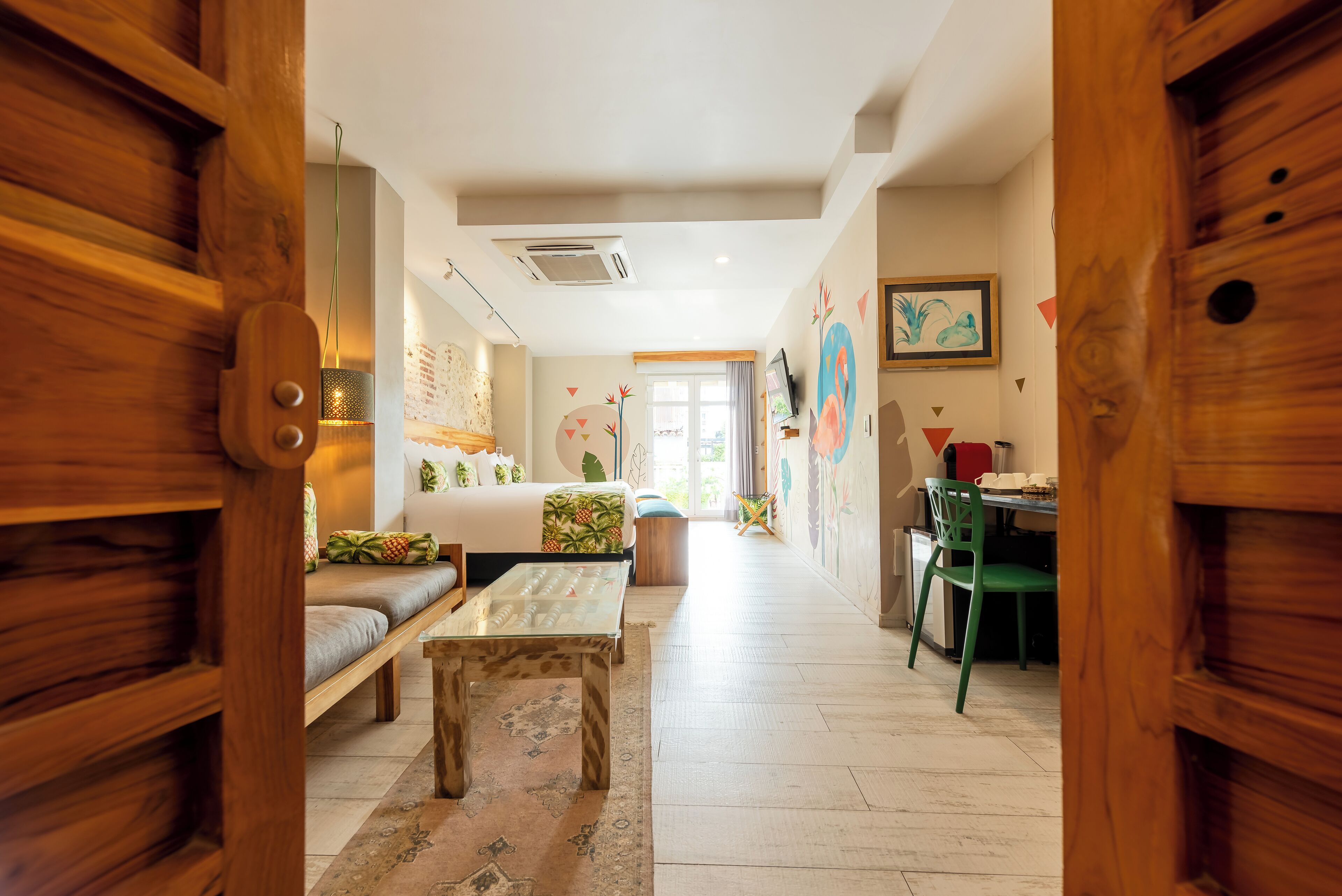 A modern interior with a wooden door, a sofa, a dining table, and a green chair.