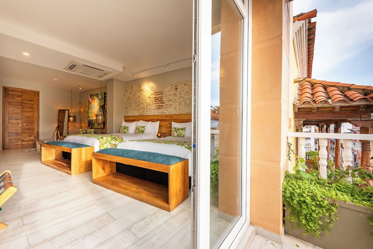 Une chambre à coucher avec un lit, deux bancs en bois, une grande fenêtre et une vue sur la ville.