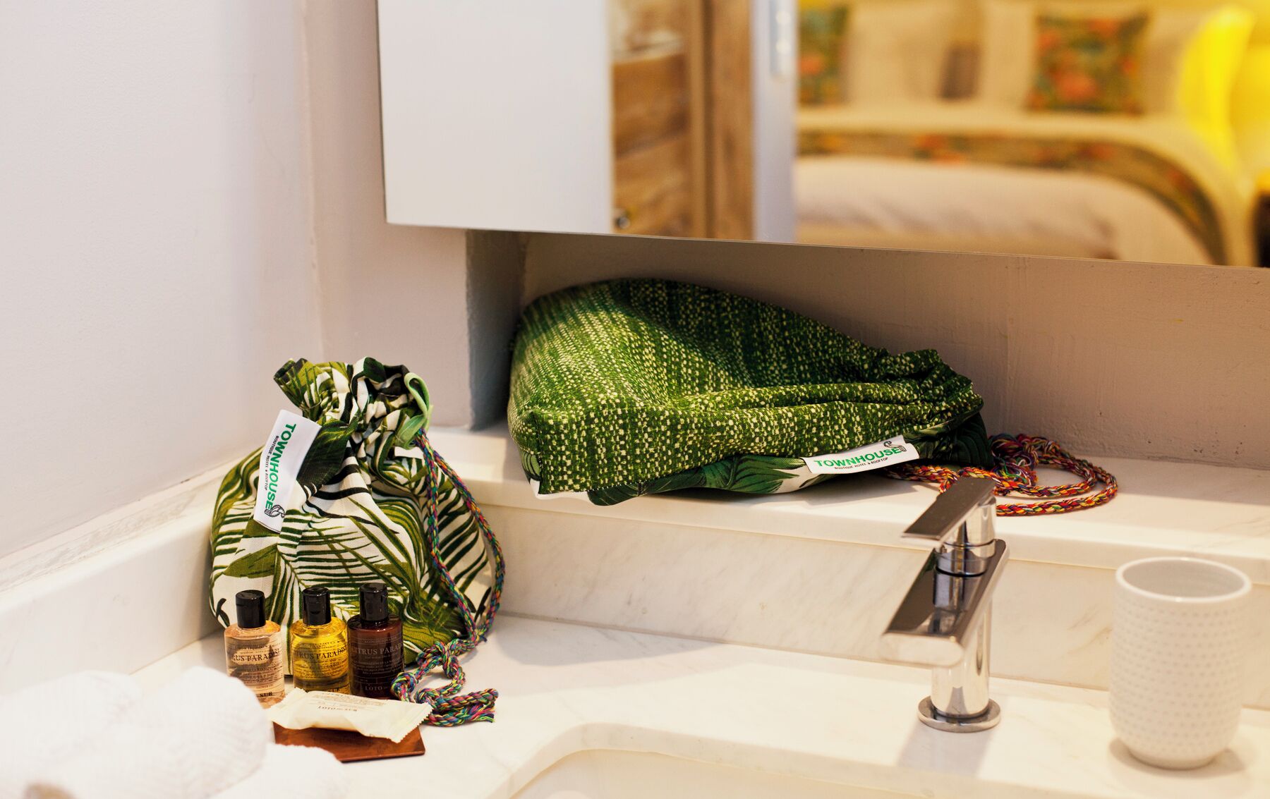 Un baño con un lavamanos blanco, un espejo y una toalla verde. Hay artículos de aseo en la encimera.