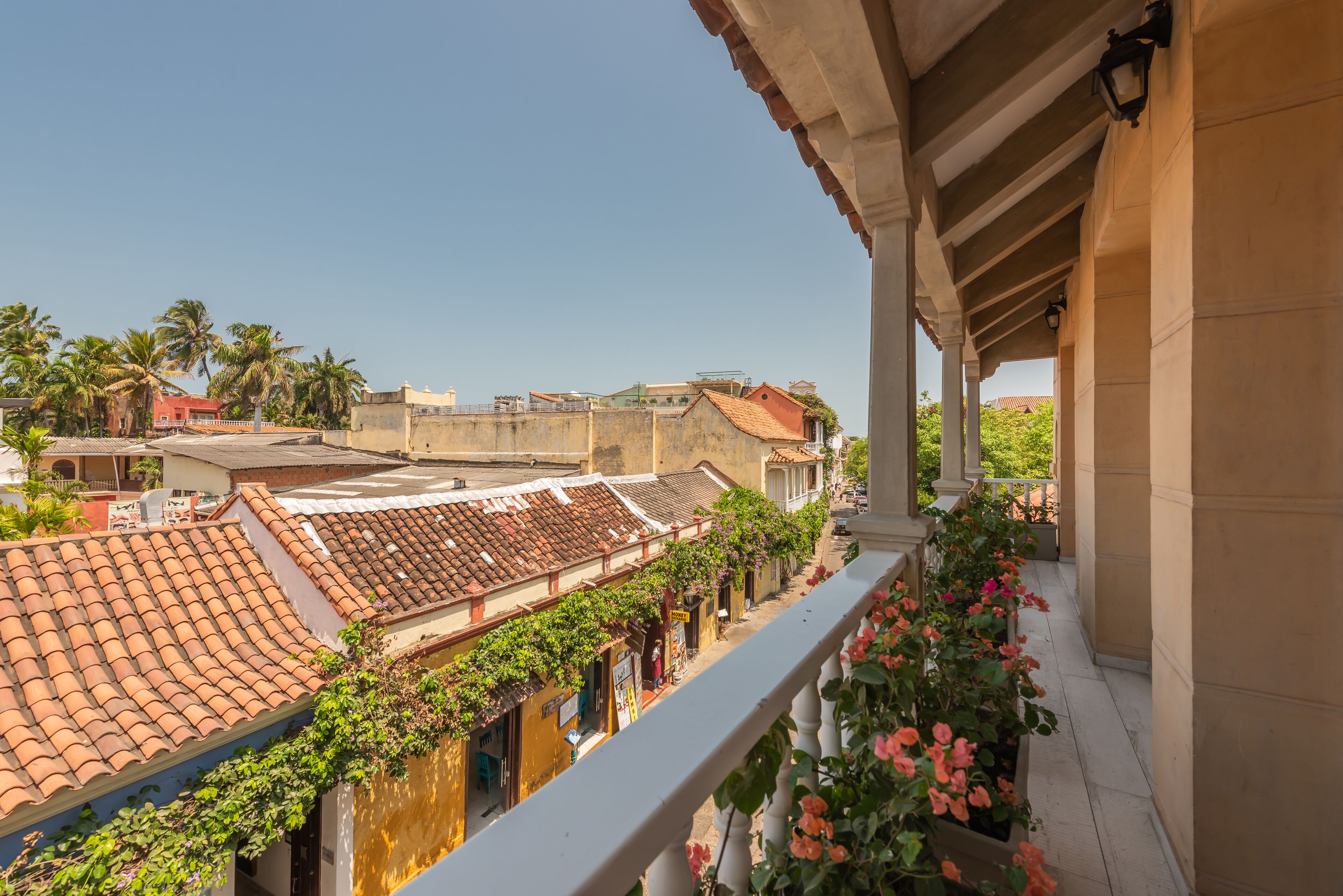 Un balcon offrant une vue sur des bâtiments aux toits de tuiles en terre cuite, un ciel dégagé et une balustrade.