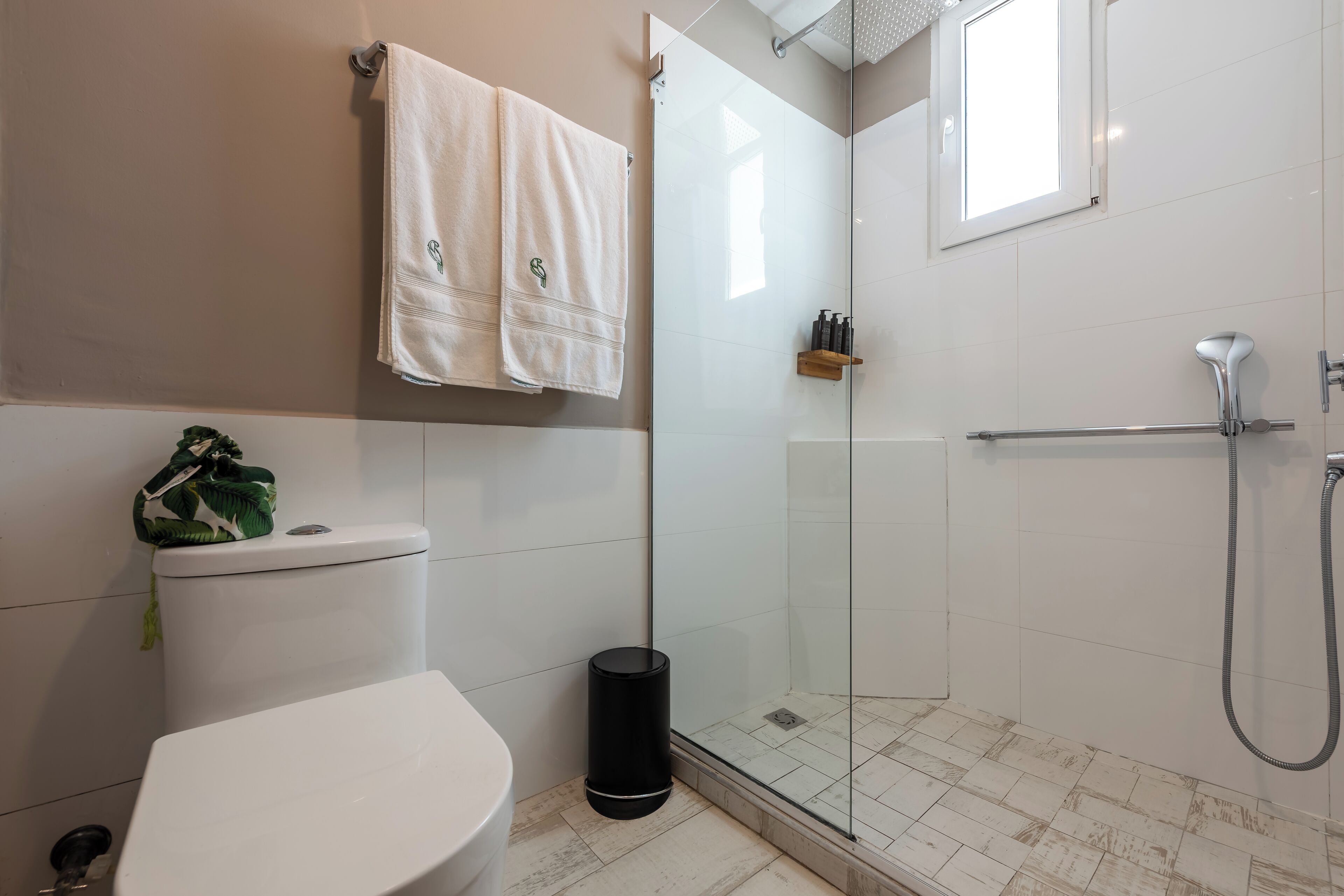 A bathroom with a toilet, a glass-enclosed shower, and a towel rack.