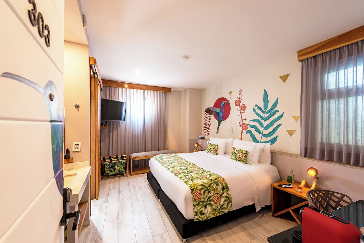 Une chambre d’hôtel avec un lit, un bureau, une télévision et un mur orné d’une fresque.
