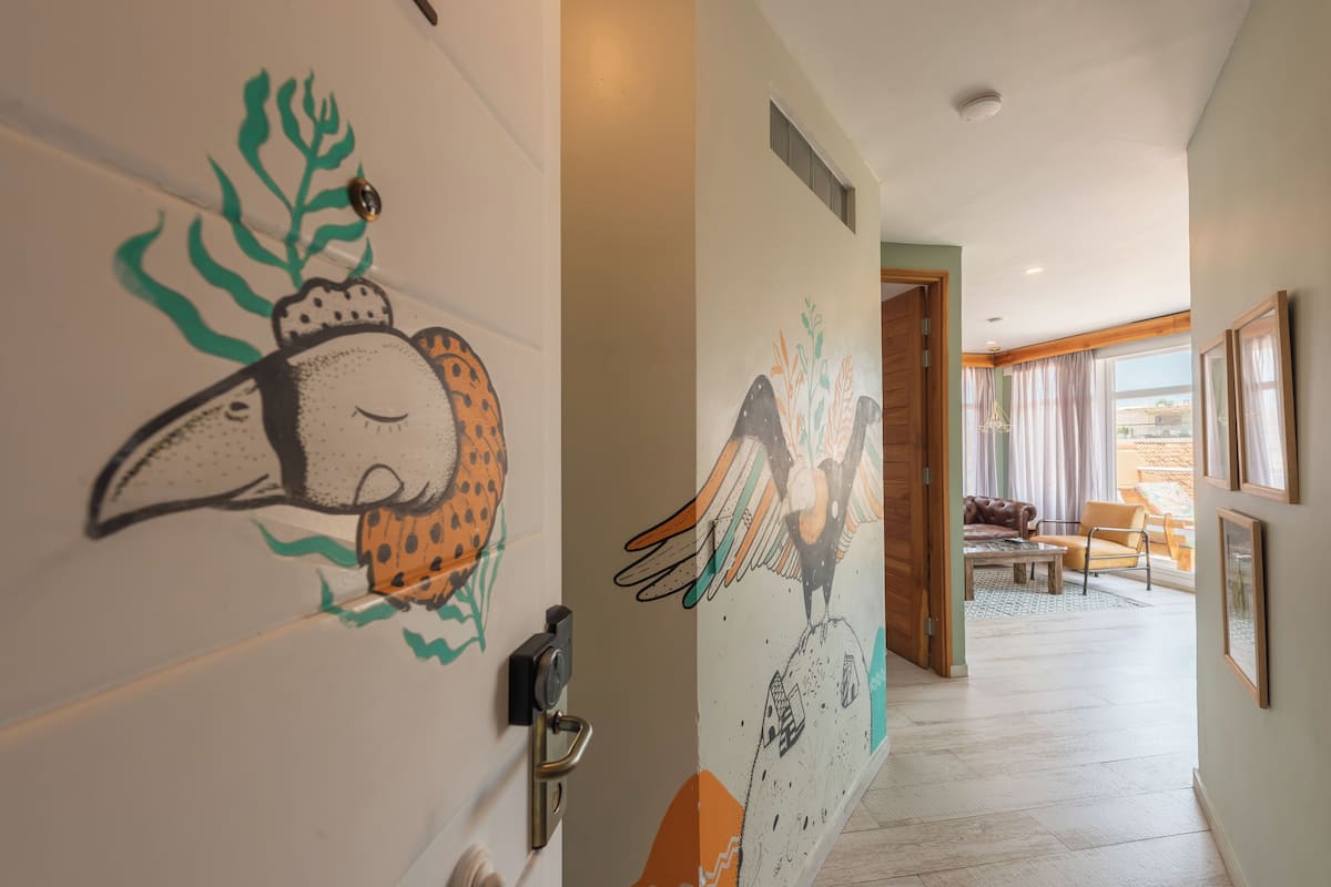 Un couloir orné d’une fresque murale représentant un oiseau et une porte dotée d’un trou de serrure.