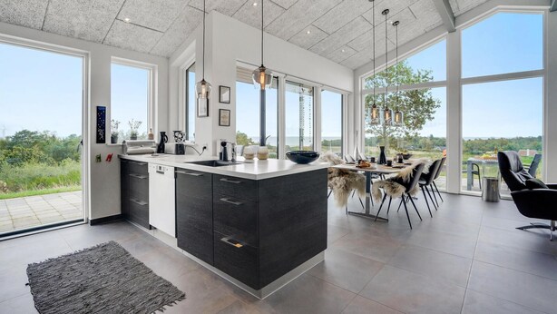 A modern kitchen with a large island, large windows, and a dining area with a view. - Nice home in Glesborg with sauna (Glesborg)
