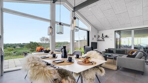 A spacious dining area with a large table, chairs, and a view of the outdoors. - Nice home in Glesborg with sauna (Glesborg)