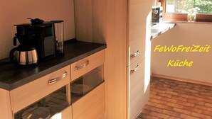 Una kitchenette con cafetera, un mueble pequeño y un ventanal con vistas a zonas verdes.
