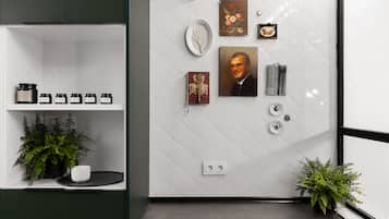 Een modern interieur met een witte betegelde muur, een plank met potten, een potplant en een lijst met een portret.
