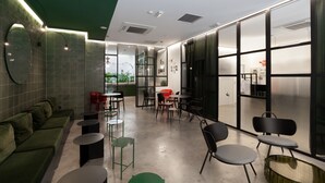 Un interno moderno con un divano verde, tavoli rotondi e sedie.