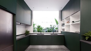 Una cucina moderna con un'ampia finestra, mobili color verde scuro e un pavimento in cemento.