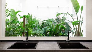 Una cucina con due lavelli neri e una finestra che si affaccia su un rigoglioso giardino.