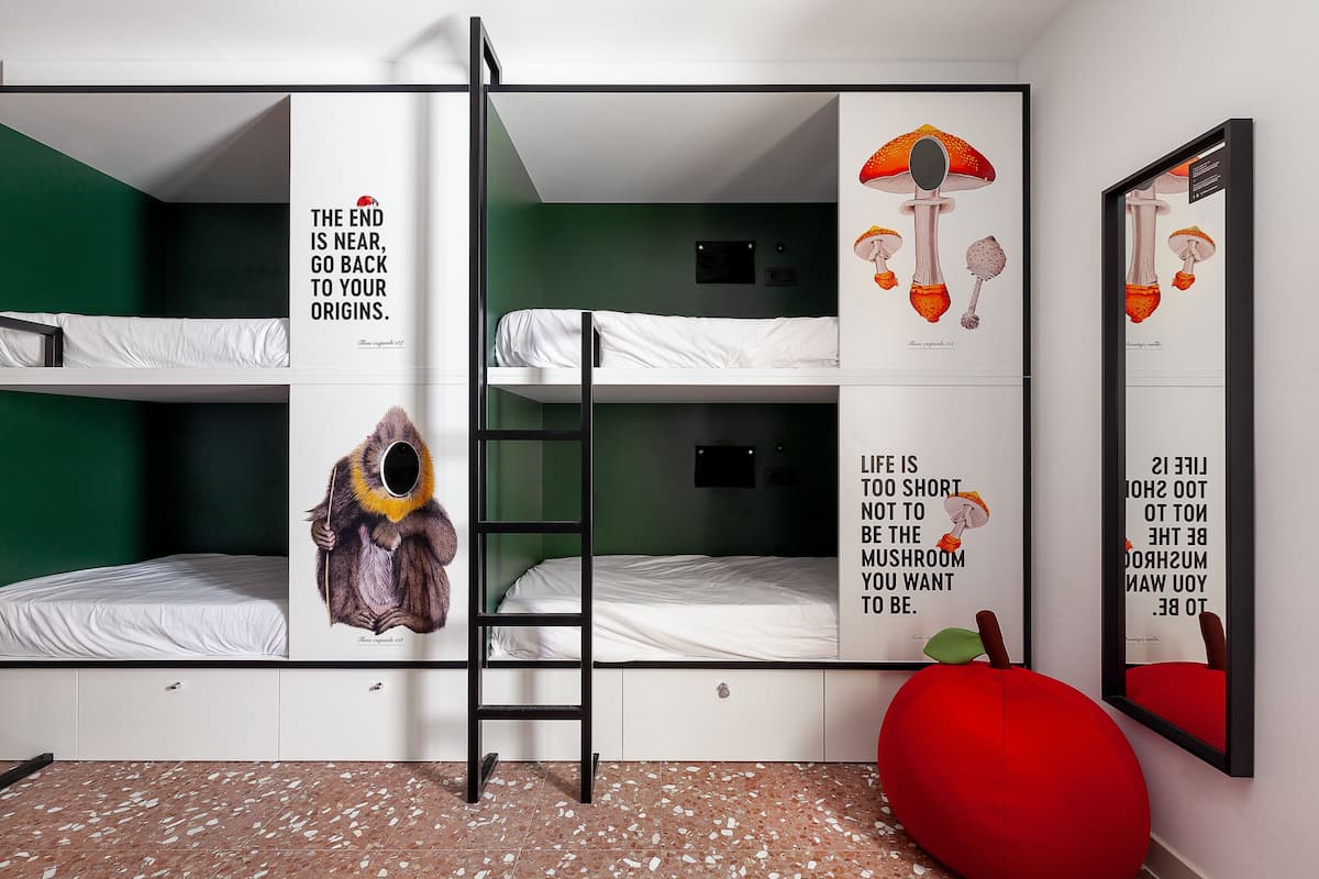 A bunk bed room with green walls, a ladder, and artwork depicting mushrooms and a monkey.