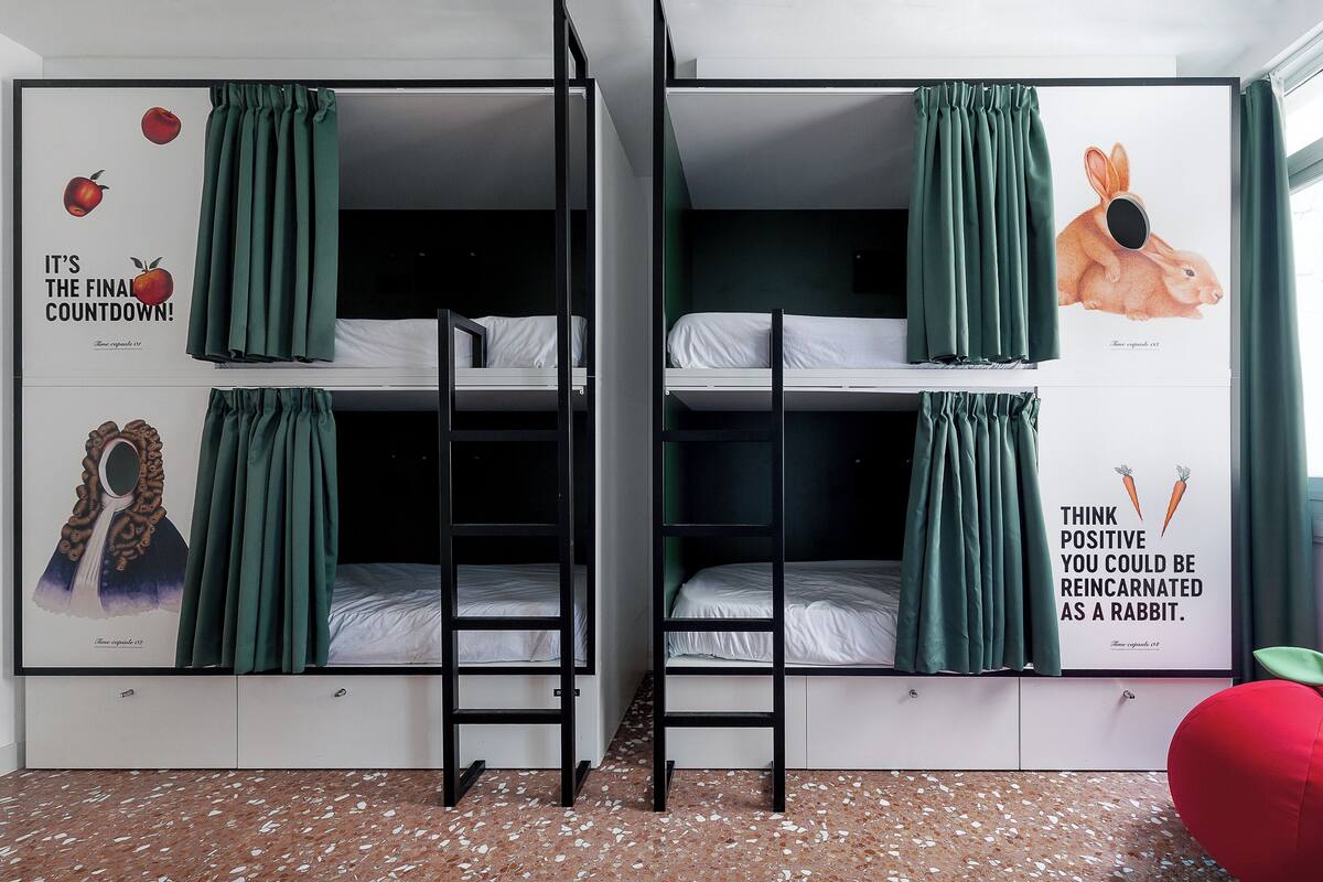 A dormitory room with bunk beds, green curtains, and motivational posters.