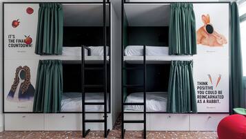 Une chambre de dortoir avec des lits superposés, des rideaux verts et des affiches motivantes.
