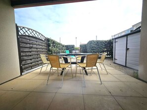 An outdoor patio with a table and chairs, a metal gate, and a garage door.