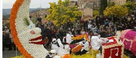 Eine öffentliche Veranstaltung mit einer großen floralen Gestaltung in Form eines Halbmonds und eines Gesichts, umgeben von Menschen.