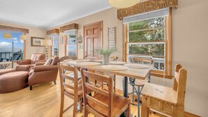 Un salon spacieux avec une table à manger en bois, des canapés en cuir et une grande fenêtre offrant une belle vue.
