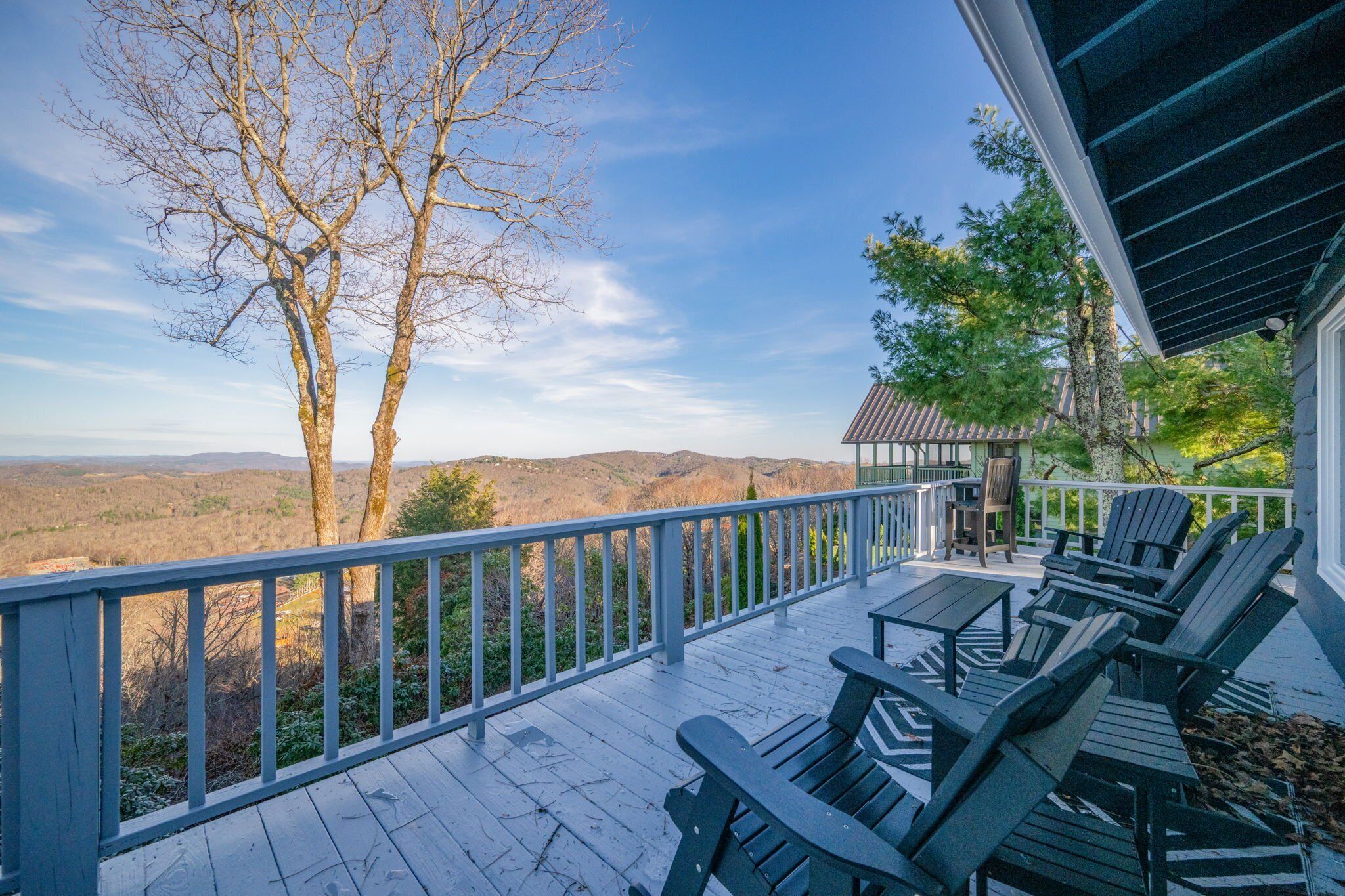 Une terrasse en bois avec des sièges extérieurs et une vue sur les montagnes.