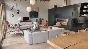 A modern living room with a fireplace, wooden dining table, and sofas.