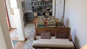 A cozy living room with a sofa, a dining table with chairs, and a kitchen area in the background.