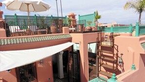 A rooftop terrace with a seating area, a staircase, and a view of the surrounding buildings. - Riad "LA DOUIRIA" in exclusivity (Marrakech)