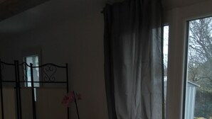 A room with a dining table and chairs, a small table with a vase, and a sliding glass door leading outside. - 2* furnished studio - La Maison aux Mille Roses (Nieul-Sur-Mer)
