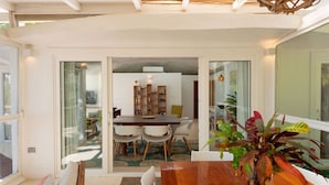 Un comedor con mesa y sillas de madera, una estantería y una planta en maceta.
