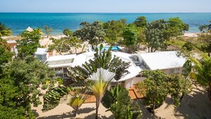 Une propriété située en bord de mer, dotée d’une piscine, de nombreuses pièces et d’une végétation luxuriante.