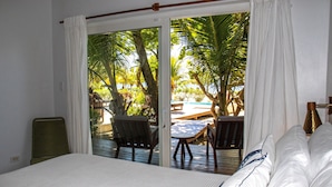Un dormitorio con cama, una silla y vistas a una terraza exterior con mesa y sillas.