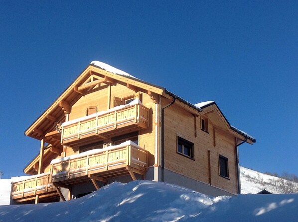 Una cabaña de madera con balcón, rodeada de nieve.