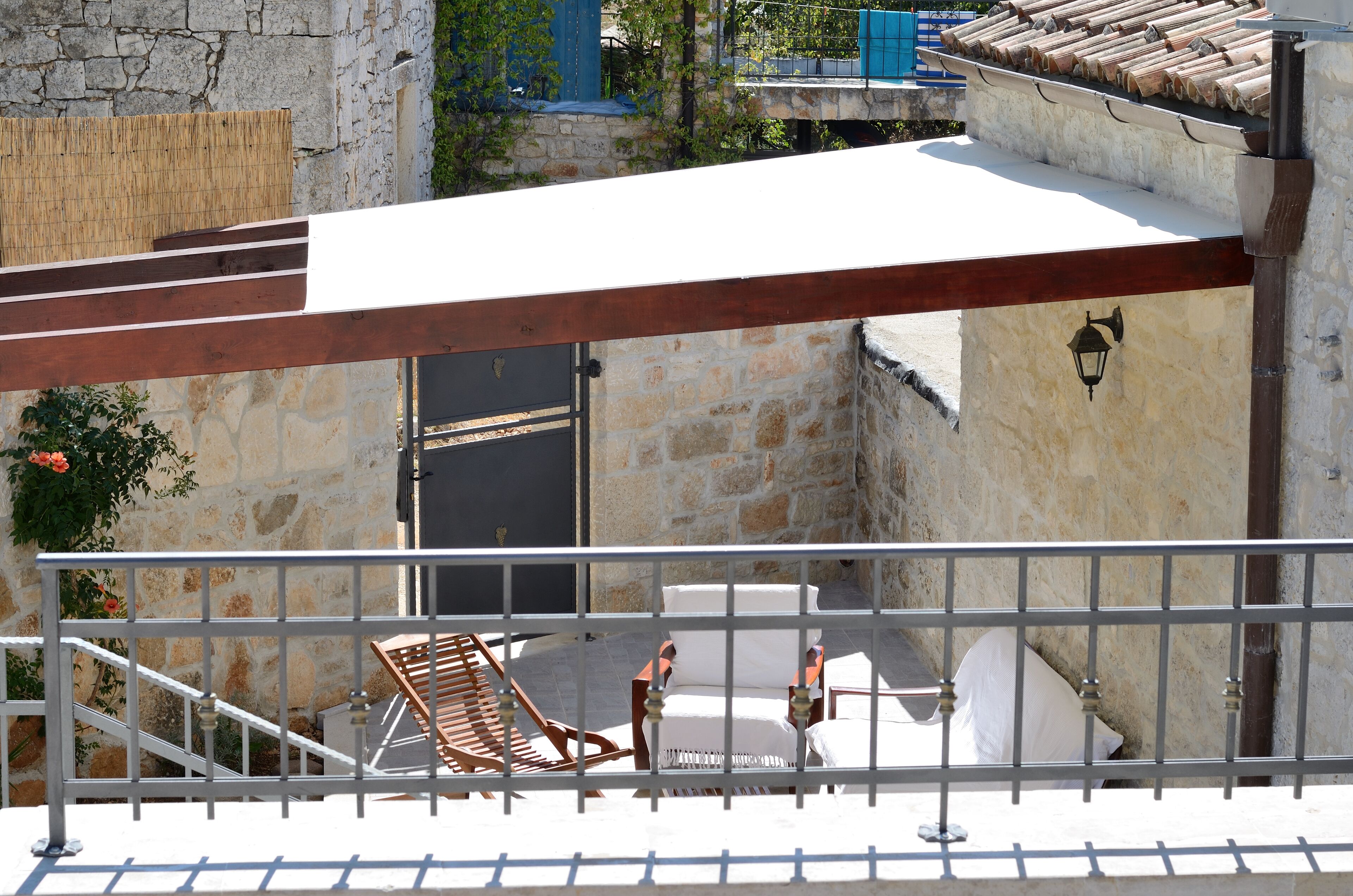 Un balcó amb una pérgola de fusta, una paret de pedra i un teulat d'aules.