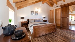 Ein Schlafzimmer mit einem Holzbett, Nachttischen, einem Beistelltisch, Holzboden und einer Decke mit sichtbaren Holzbalken.