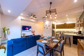 Une cuisine moderne dotée d’un îlot central, d’un coin repas avec un canapé bleu et d’un ventilateur de plafond.