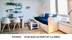 Un estudio con cama, escritorio, sillas y ventana.