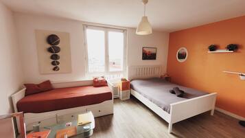Une chambre avec deux lits, une table en verre, une fenêtre et un luminaire au plafond.