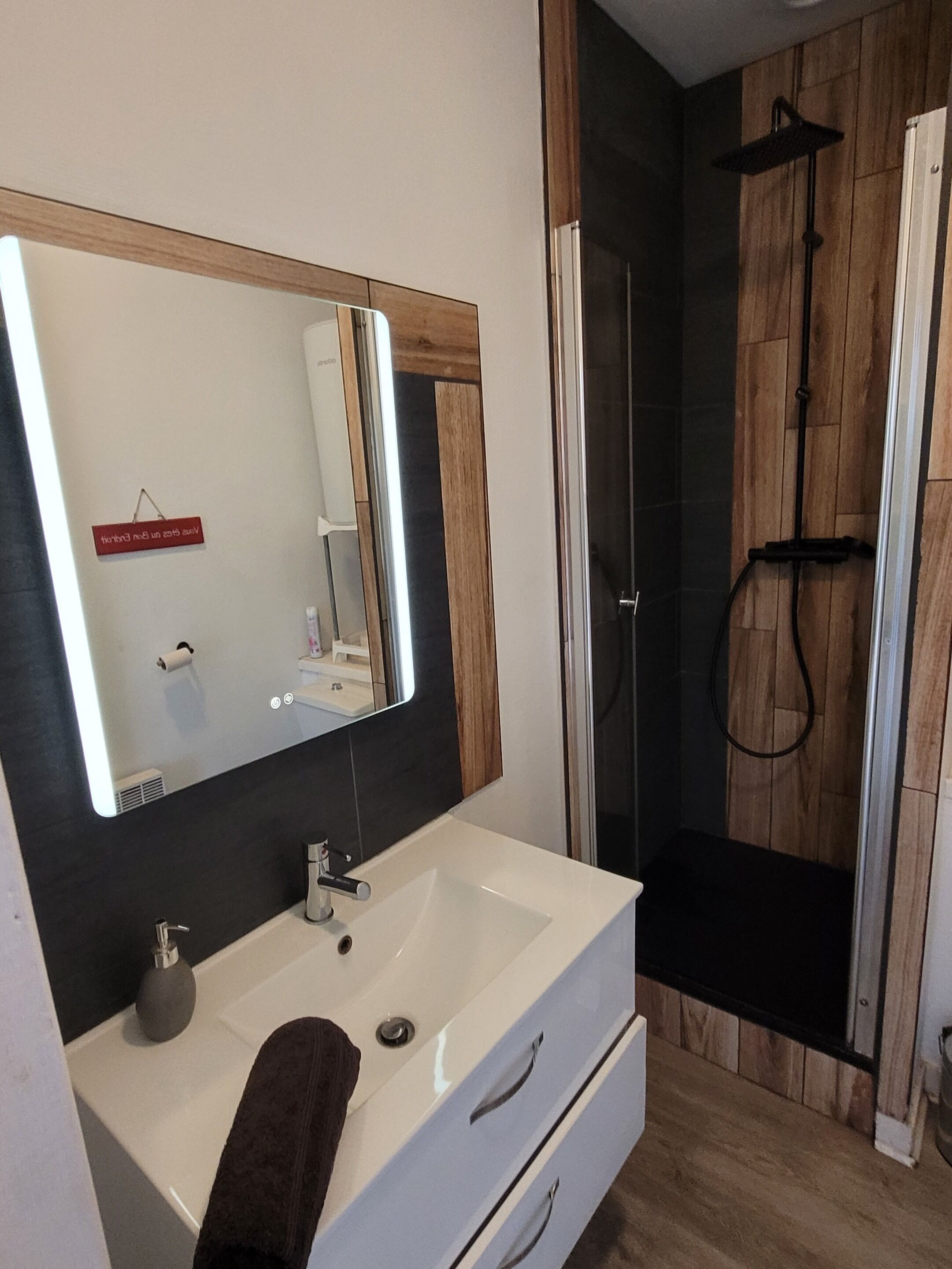 Een moderne badkamer met een wit wastafel, een grote spiegel en een douche met glazen wanden.