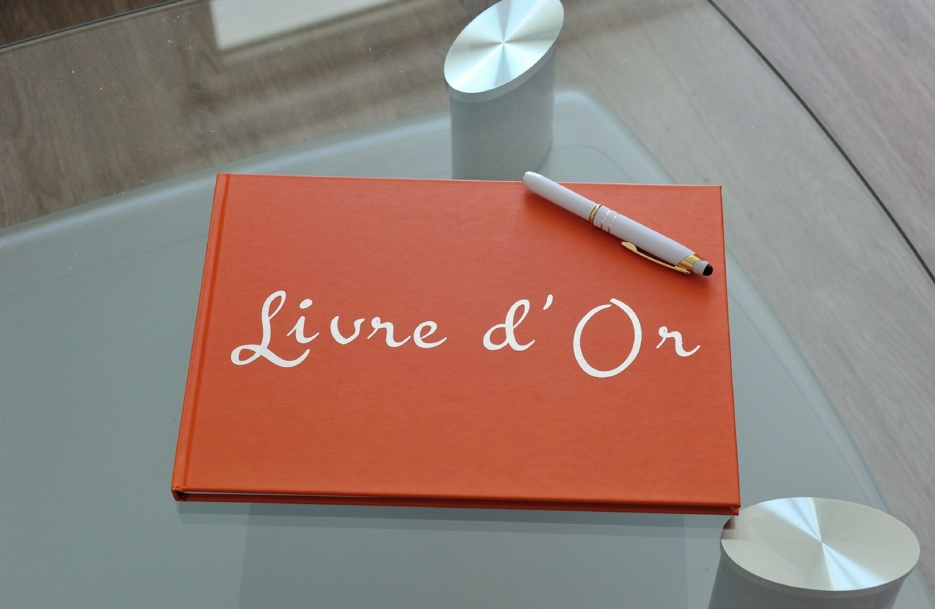 A book titled "Livre d'Or" on a glass table with a pen on top.
