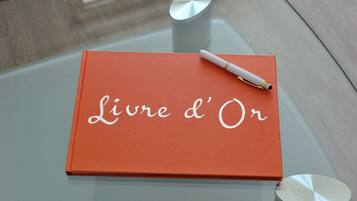 A book titled "Livre d'Or" on a glass table with a pen on top.