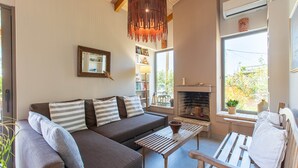 Un salon avec un canapé, une table en bois, une cheminée et une fenêtre donnant sur un beau paysage.
