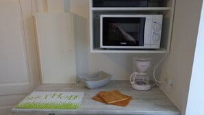 A kitchen with a microwave, coffee maker, and a bowl on the counter.