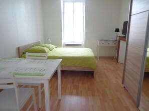 Cozy bedroom with a single bed, desk, and nightstand, perfect for a restful stay.