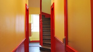 A narrow hallway with red doors and yellow walls, leading to a staircase.