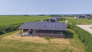 Une maison moderne dotée d’une grande terrasse et d’un patio couvert.
