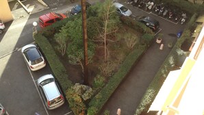 A parking lot with several cars and motorcycles, surrounded by greenery and trees.