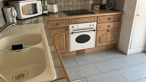 A compact kitchen with wooden cabinets, a microwave, a toaster, and a built-in oven.