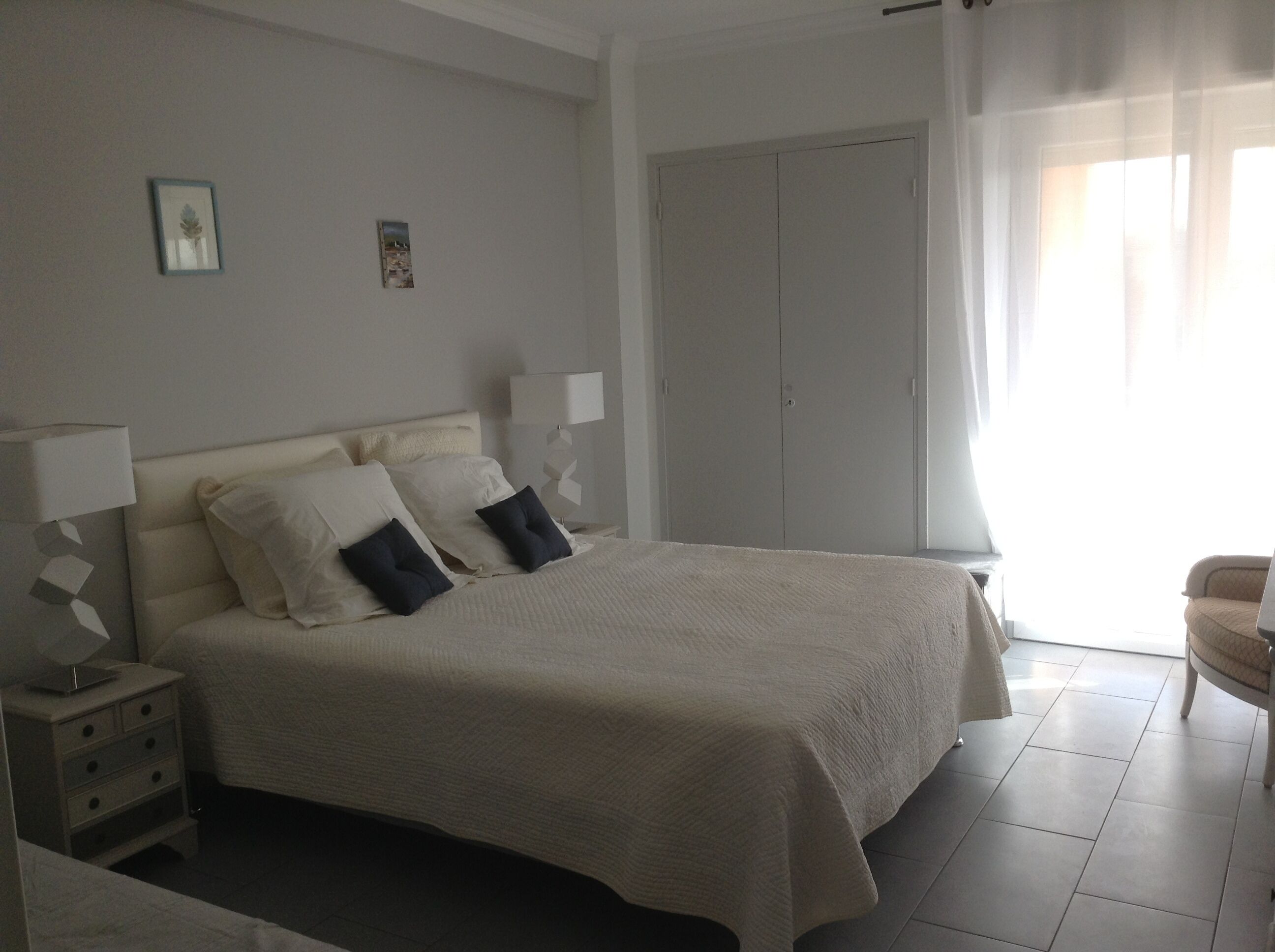 Une chambre à coucher comprenant un lit, des tables de chevet, une armoire et une chaise.